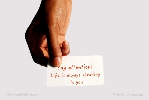Hand holding out a card that reads: Pay attention, life is always speaking to you
